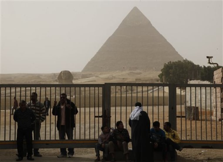 Egyptian tourist guides and security on Saturday sit near the pyramids in Giza, Egypt. The military has closed the pyramids to tourists following unrest in Cairo, the nation's capital.